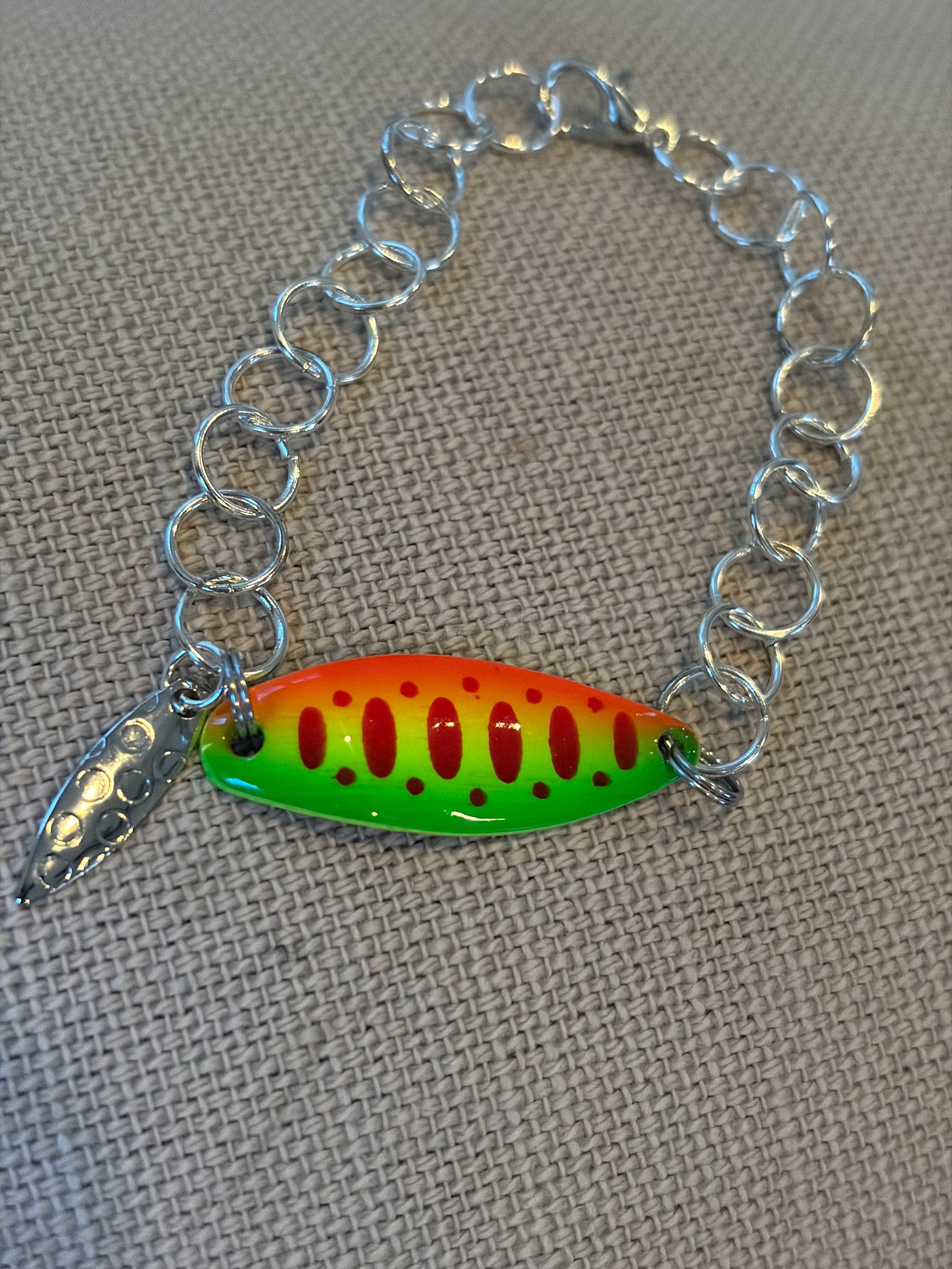 Bracelet with a colorful fishing lure charm on a textured surface