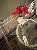 Bracelet with red ribbon and 'live your dream' charm on a glass surface