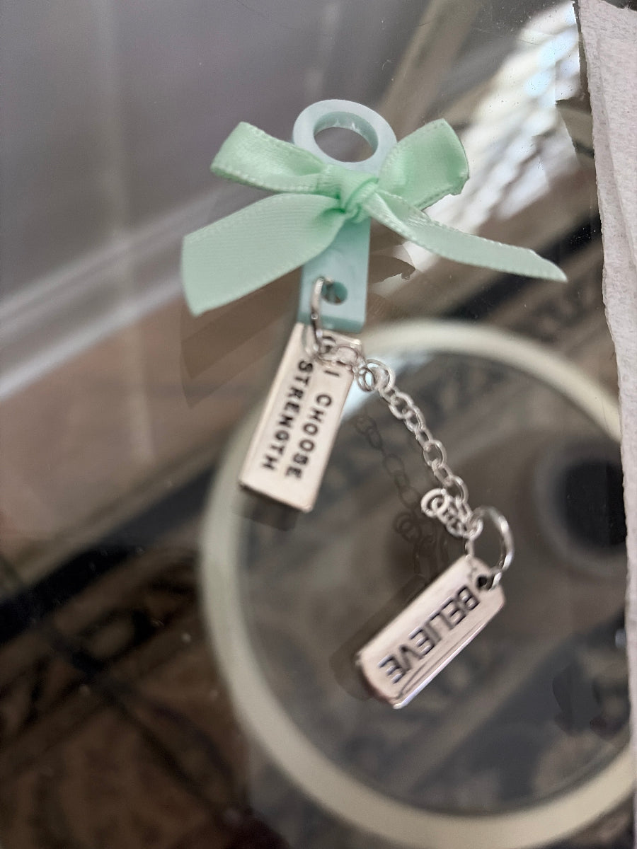 Keychain with motivational pendants and a ribbon on a reflective surface